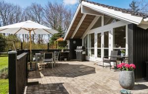 a patio with an umbrella and tables and chairs at Awesome Home In Ulfborg With Wifi in Ulfborg +18 photos