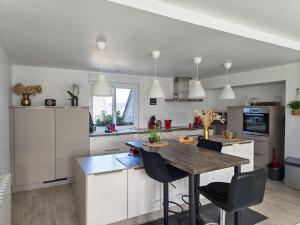 a kitchen with white cabinets and a wooden table at Macleo proche plage in Plougasnou