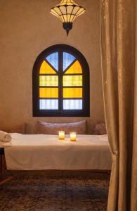 a bed with two candles in front of a window at Riad Aïcha Addi Pool & Hammam in Essaouira +57 photos