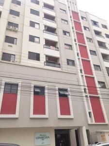 un edificio alto de color blanco con puertas y ventanas rojas en Apartamento Balneário Camboriú, en Balneário Camboriú
