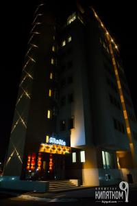 a building with a sign on top of it at night at GREEN Which Hotel in Kokshetau