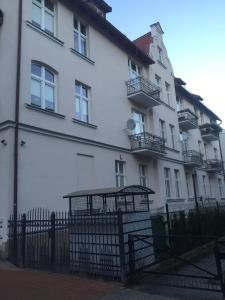 a white building with a fence in front of it at Mieszkanie przy deptaku Sopot in Sopot