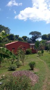 a red building in a yard with trees and bushes at Villa Marie in Nosy Be