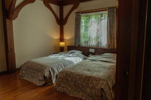 two beds in a bedroom with a window at 山あいの静かなログハウス Quiet Mountain Log House with Indoor Hot Spring Bath in Gujo