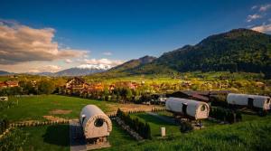 an aerial view of a farm with mountains in the background at Nomad by Hora cu Brazi in Zărneşti