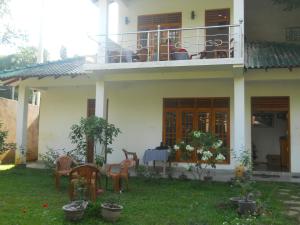 a house with a balcony with a table and chairs at Sunset Tourist Home in Polonnaruwa