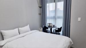 a bedroom with a white bed and a table with chairs at 썸원호텔 in Yŏsu +20 photos