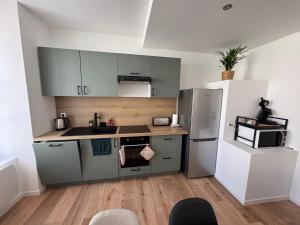 a kitchen with gray cabinets and a refrigerator at L'hotel de ville in Chéroy