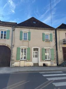 an old house with green shutters on a street at L'hotel de ville in Chéroy