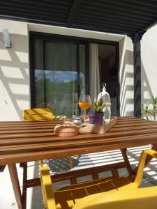 a wooden table with yellow chairs and a glass of wine at studio des olivières in Montpeyroux