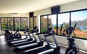 eine Reihe von Heimtrainern in einem Fitnessraum mit Fenstern in der Unterkunft Marina Fiesta Resort & Spa, A La Carte All Inclusive Optional in Cabo San Lucas