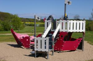 um parque infantil com equipamento vermelho e branco num parque em Treibgut & Surf em Dranske