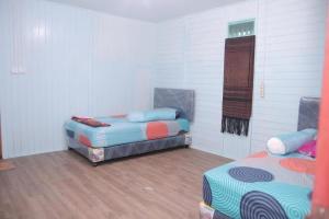 two beds in a room with white walls and wooden floors at Zena Cottage in Ende
