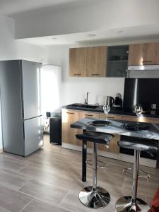 a kitchen with a refrigerator and two bar stools at Le petit Vittel in Vittel
