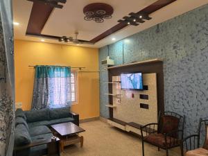 a living room with a couch and a tv at The Green residence in Mysore