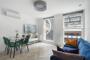 a living room with a blue couch and a table at Modern Apartment Charing Cross - Aircon in London