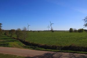 a field of grass with windmills in the distance at Ferienwohnung Am Sieler in Südbrookmerland