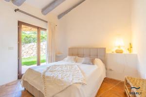 a bedroom with a large white bed with a window at Villa Domo Mea - By Searly in Porto Cervo +65 photos