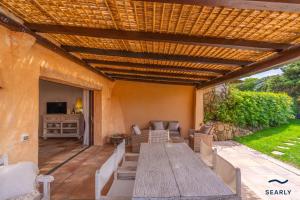 an outdoor patio with a wooden table and chairs at Villa Domo Mea - By Searly in Porto Cervo