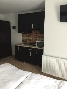 uma cozinha com armários pretos e uma cama num quarto em Mini-hotel Megora em Rakhiv