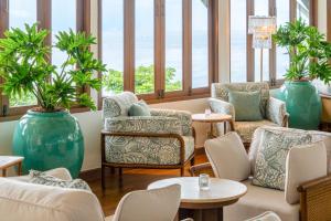 a waiting room with chairs and tables and windows at Cape Panwa Hotel Phuket in Panwa Beach +98 photos