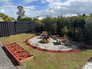 a backyard with a fire pit and a bench and flowers at Country Tracks in Willowbank +5 photos