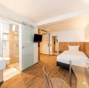 ein Schlafzimmer mit Bett, Tisch und Fernseher in der Unterkunft Hotel Ross in Schweinfurt