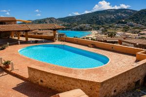 a large swimming pool on a patio next to a house at Baja Sardinia Casetta Belvedere 2 with Pool 100m from the Beach in Baja Sardinia