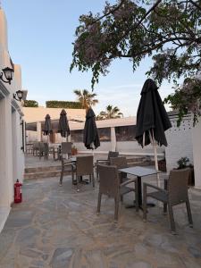 a patio with tables and chairs and umbrellas at Romantika in Platis Gialos