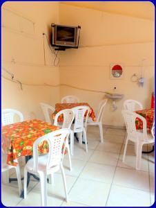 comedor con sillas y mesas blancas y TV en Hospedaria Praia e Sol, en Fortaleza