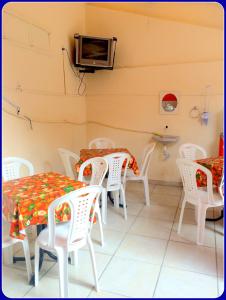 a dining room with white chairs and tables and a tv at Hospedaria Praia e Sol in Fortaleza