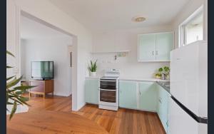 a kitchen with white cabinets and a white refrigerator at Bungo Beach Shack in Eden