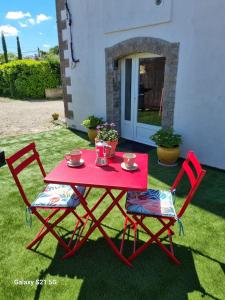 a red table and two chairs on the grass at L'escapade des Cévennes in Rousson