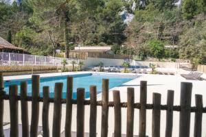 a swimming pool seen through a fence at Camping de la Vallée Heureuse in Orgon