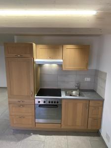 a kitchen with wooden cabinets and a stove and a sink at Le Cras in Soubey