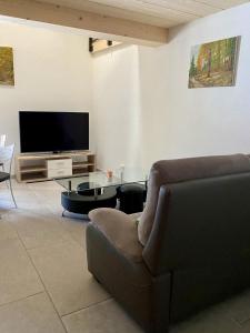 a living room with a couch and a tv at Le Cras in Soubey
