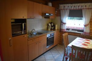 a kitchen with wooden cabinets and a sink and a table at Ferienwohnung Angela in Thalfang +11 photos