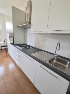 a kitchen with white cabinets and a sink at Appartamento Silva in Gorizia