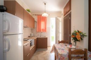 a kitchen with a table and a white refrigerator at Nisaki Summer Stay Studios in Agia Ermioni