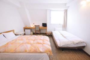a bedroom with two beds and a desk and a window at Sakura Hotel Ikebukuro in Tokyo