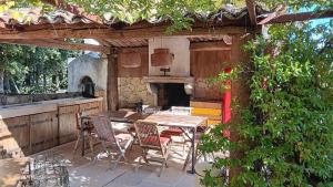 a patio with a table and chairs and an oven at Le mas des louquiers in Mons