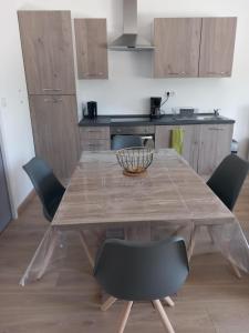 a dining room table with chairs and a kitchen at L'Olivier in Les Mazures