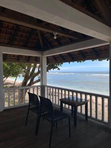 a porch with chairs and a table and the ocean at Damar Tree Resort in Krui