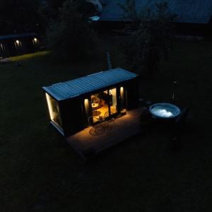 a small house with a blue roof in the dark at Reborn Cabins in Pabaži