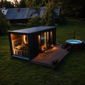 a black tiny house with a bed and a hot tub at Reborn Cabins in Pabaži