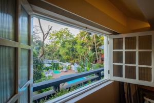 a window view of a garden from a house at Goan Bliss Alaya Stays by ELIVAAS in Varca