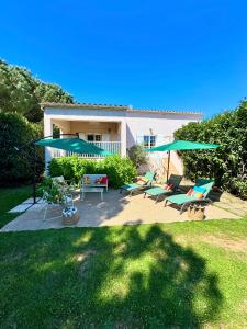 a patio with chairs and umbrellas in front of a house at Campo Vecchio Kamerops et piscine in Ghisonaccia