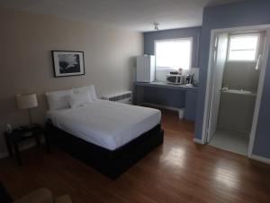 a bedroom with a white bed and a kitchen at Wheel Inn Motel in New Liskeard