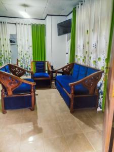 a living room with two blue couches and green curtains at Friendship Villa-Ella in Nikawatawana