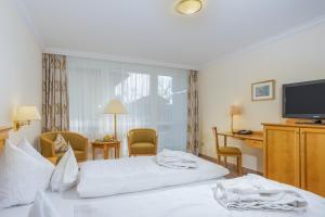 a hotel room with two beds and a flat screen tv at Hotel Bayerischer Hof in Bad Füssing +14 photos